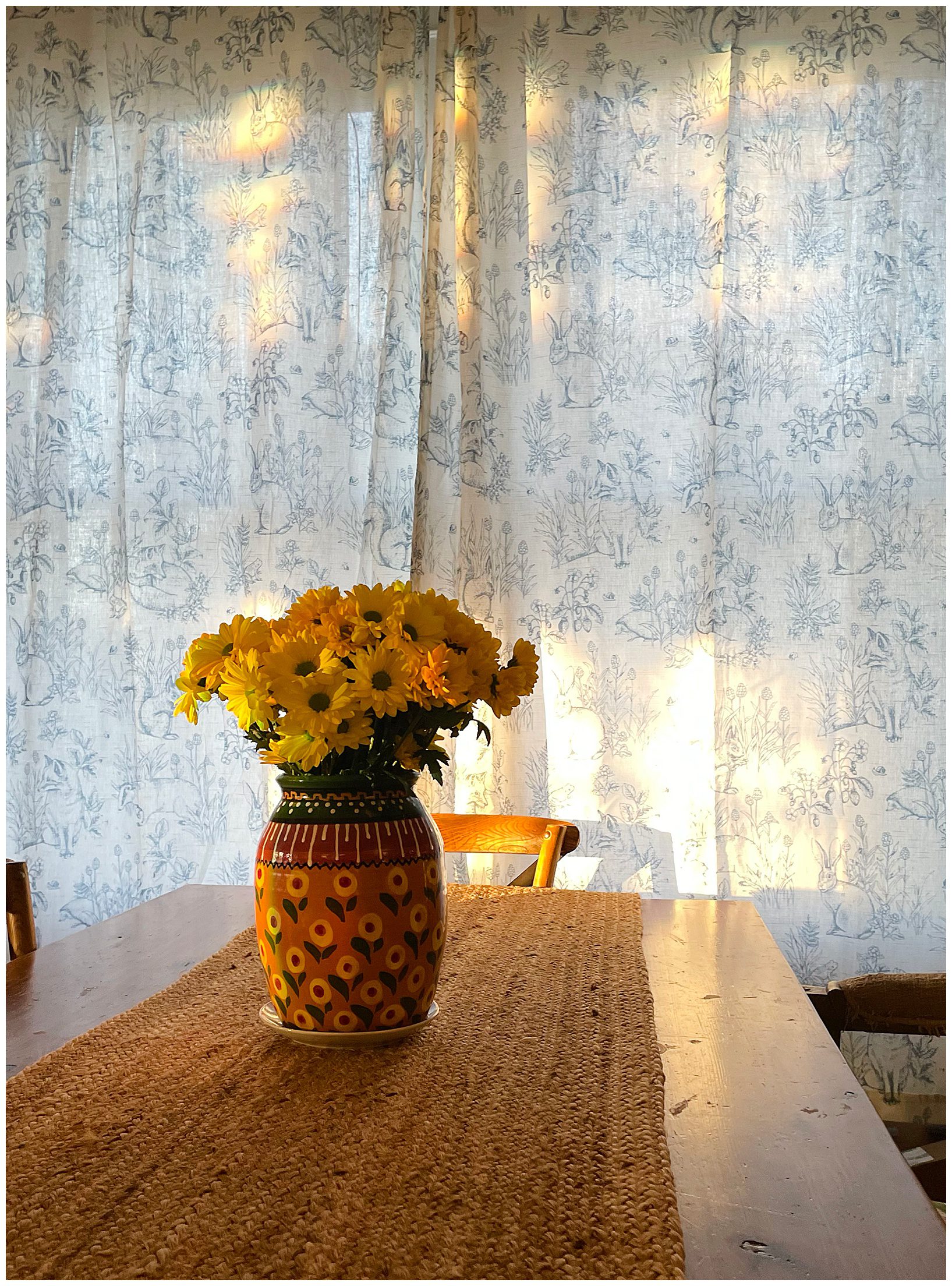 a vase with yellow flowers sits on a table