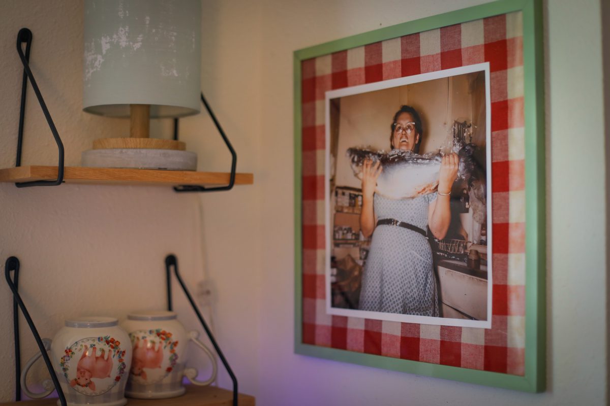 A picture of a woman holding a fish in a frame next to coffee mugs.